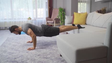 Strong-fit-young-man-doing-push-ups-on-floor-of-modern-apartment.